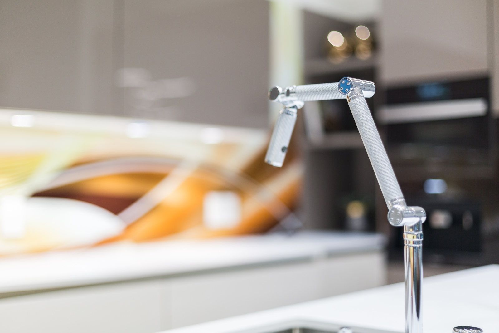 A close up of a faucet in a kitchen with a blurred background.