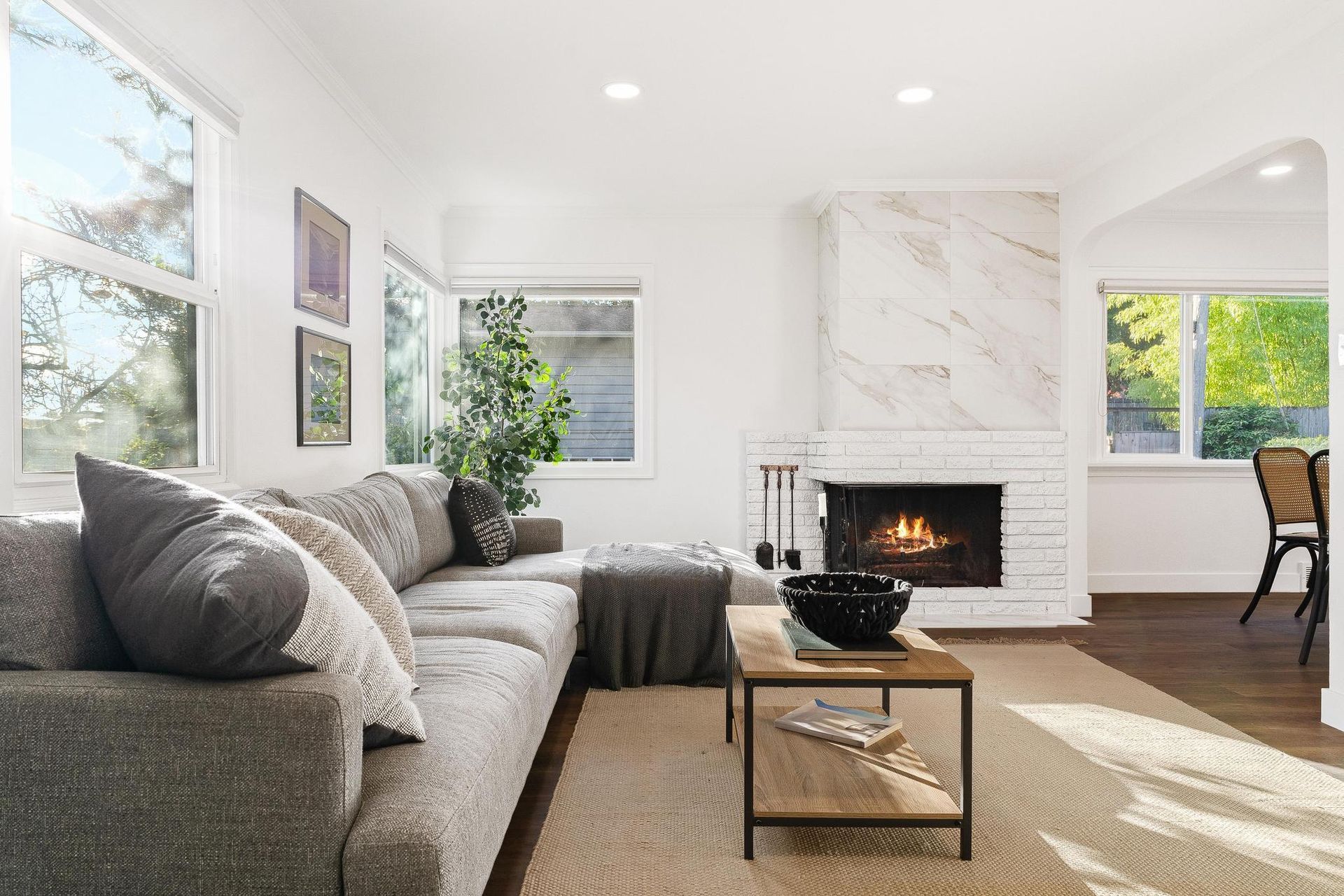 A living room with a couch , coffee table , fireplace and windows.