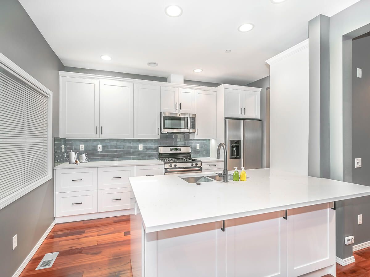 A kitchen with white cabinets , stainless steel appliances , and a large island.