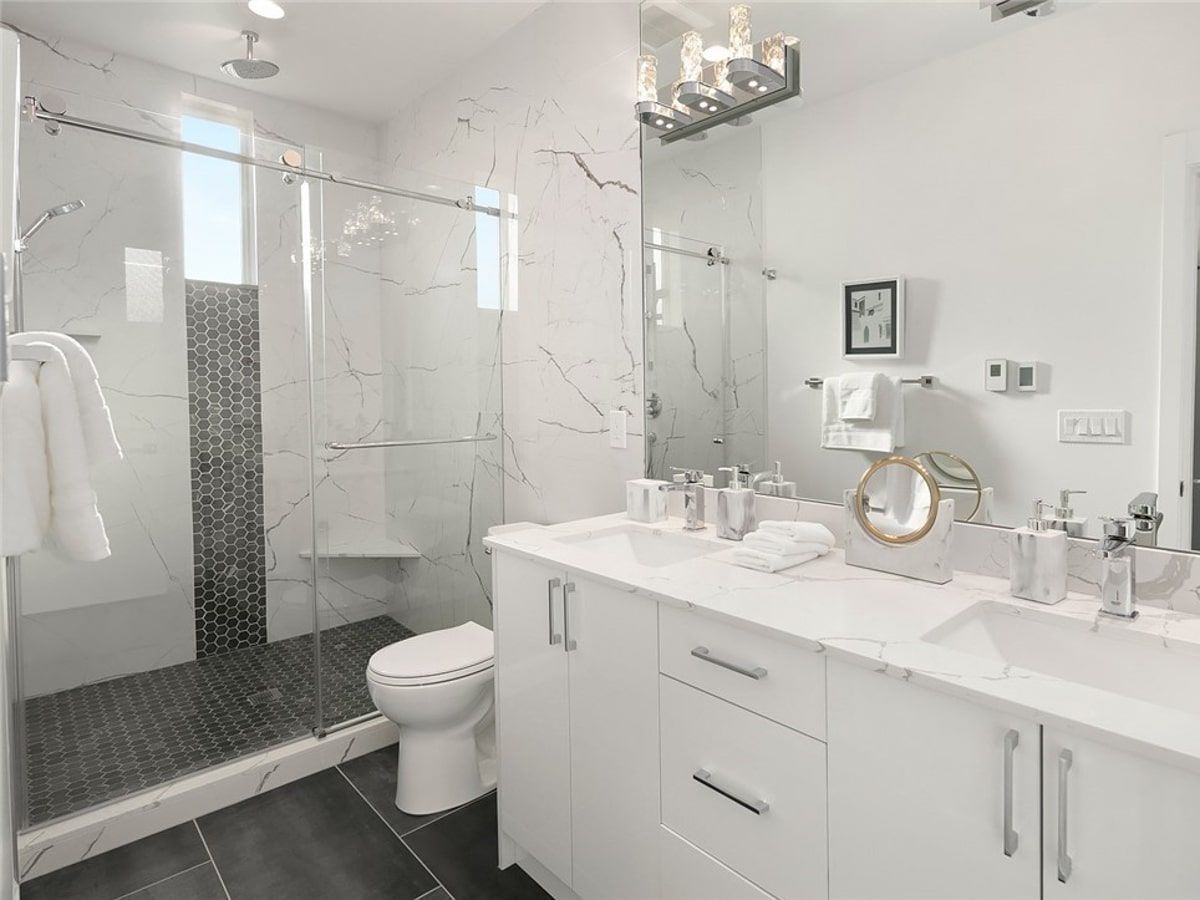 A bathroom with a toilet , sink , mirror and walk in shower.