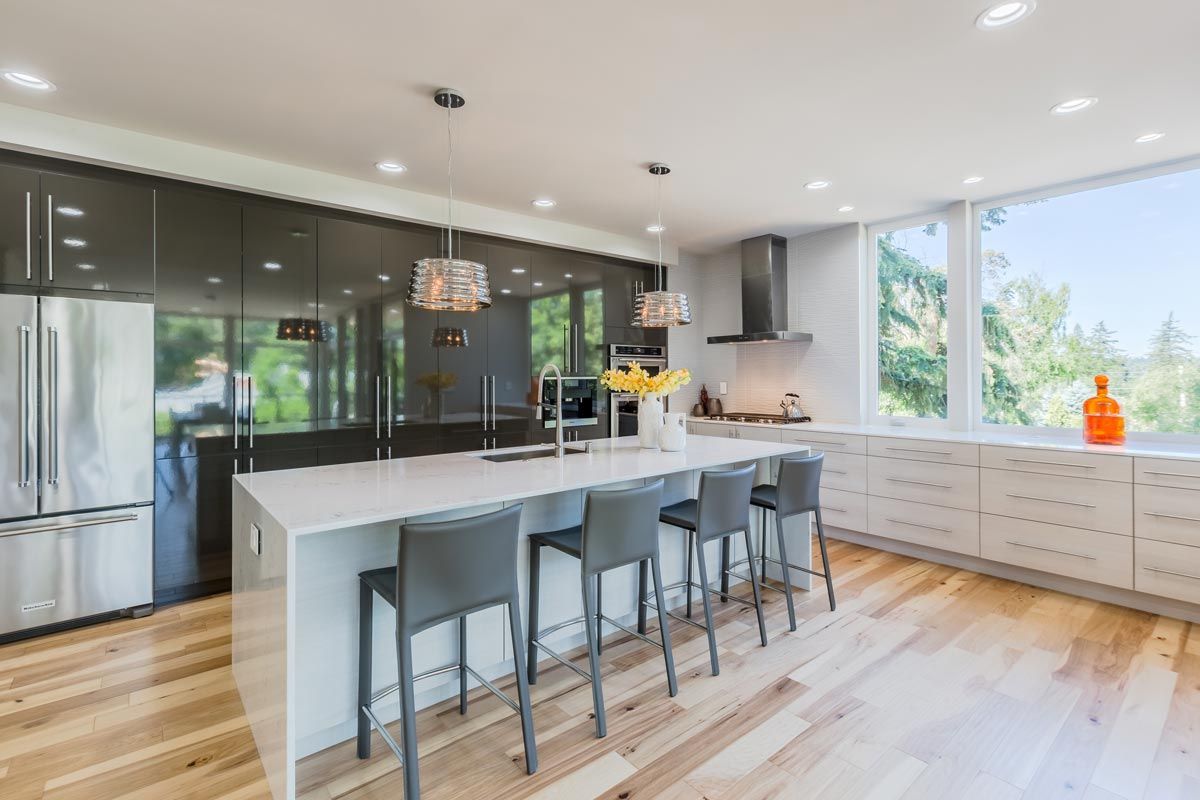 A kitchen with a large island , stools and a refrigerator.