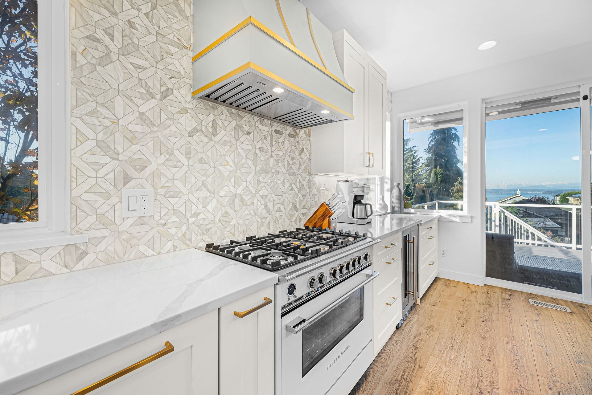 A kitchen with white cabinets , a stove top oven , and a large window.