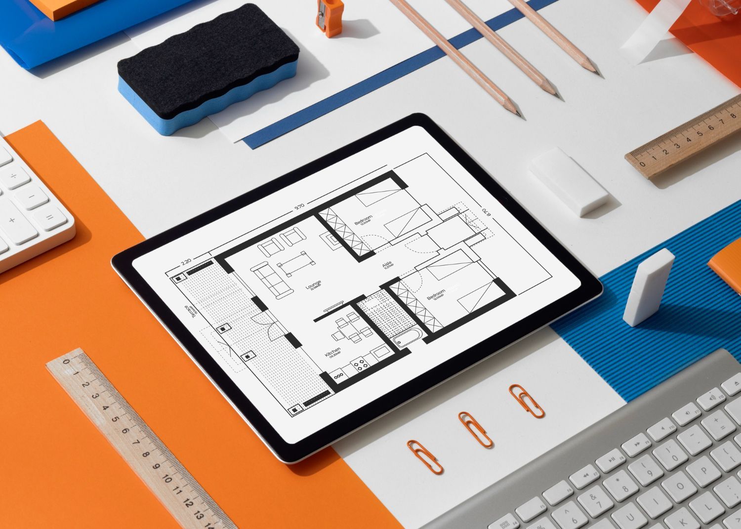 A tablet with a floor plan on it is surrounded by office supplies.