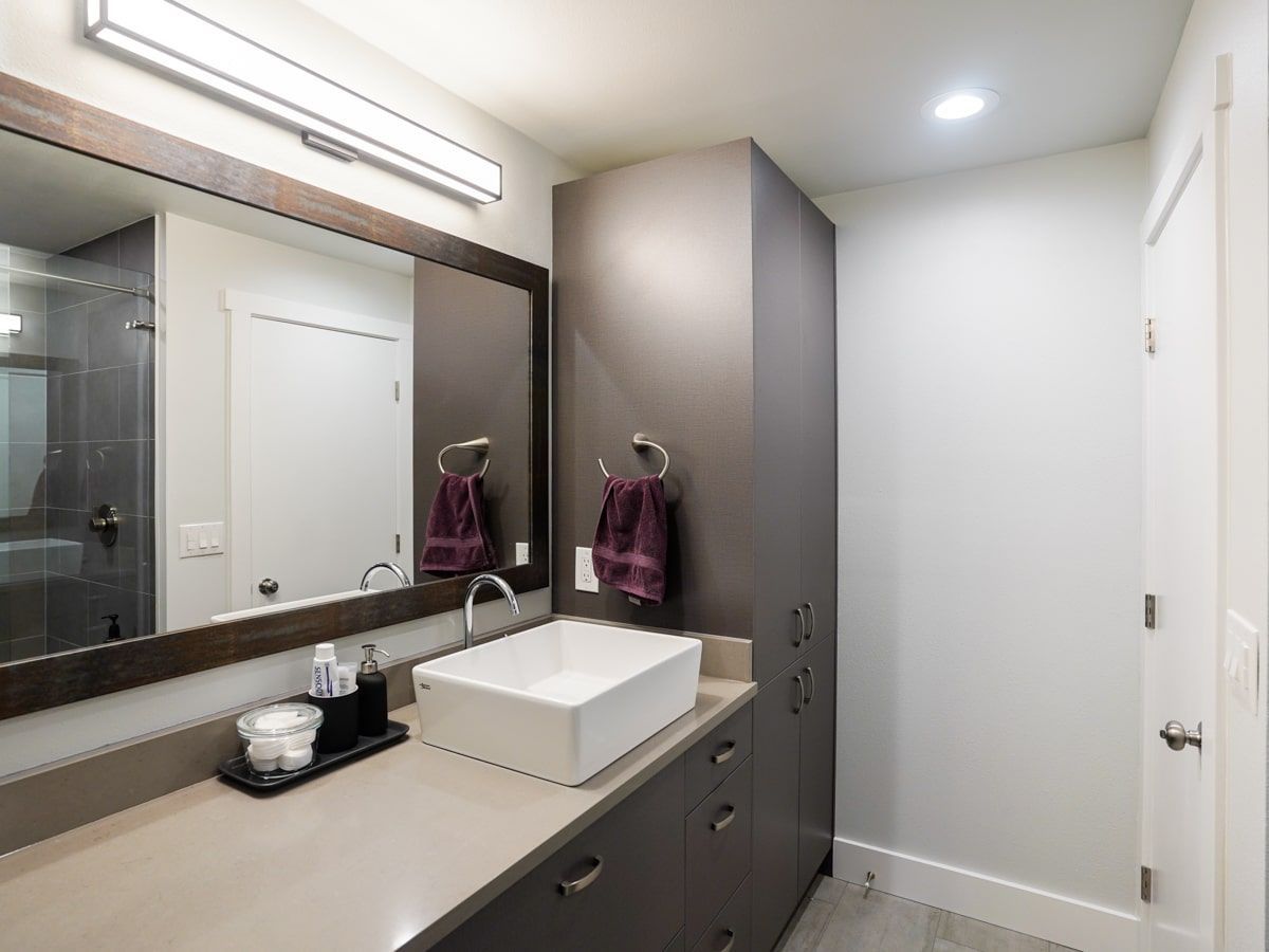 A bathroom with a sink , mirror and cabinets.