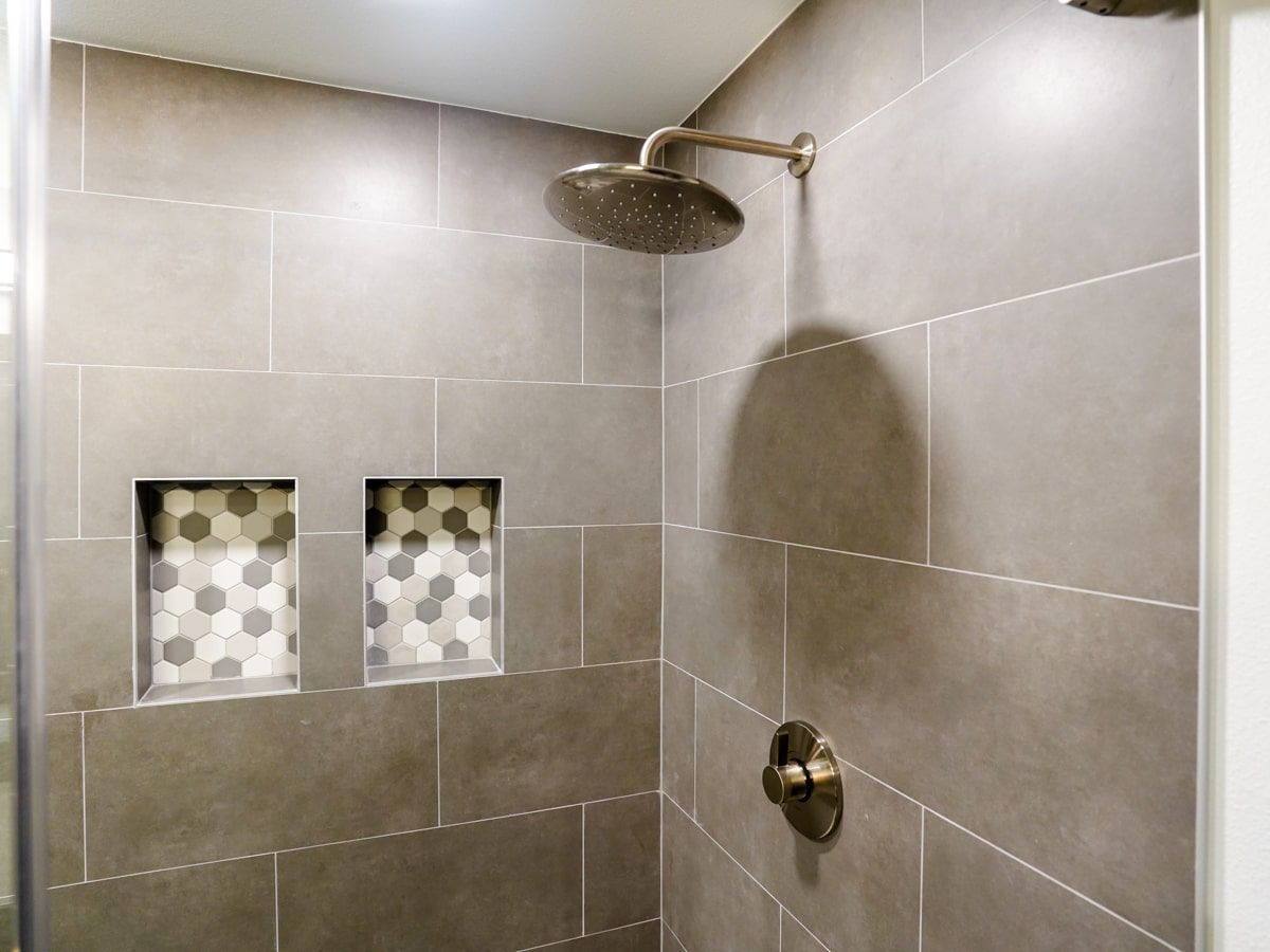 A shower with a shower head and two niches on the wall.