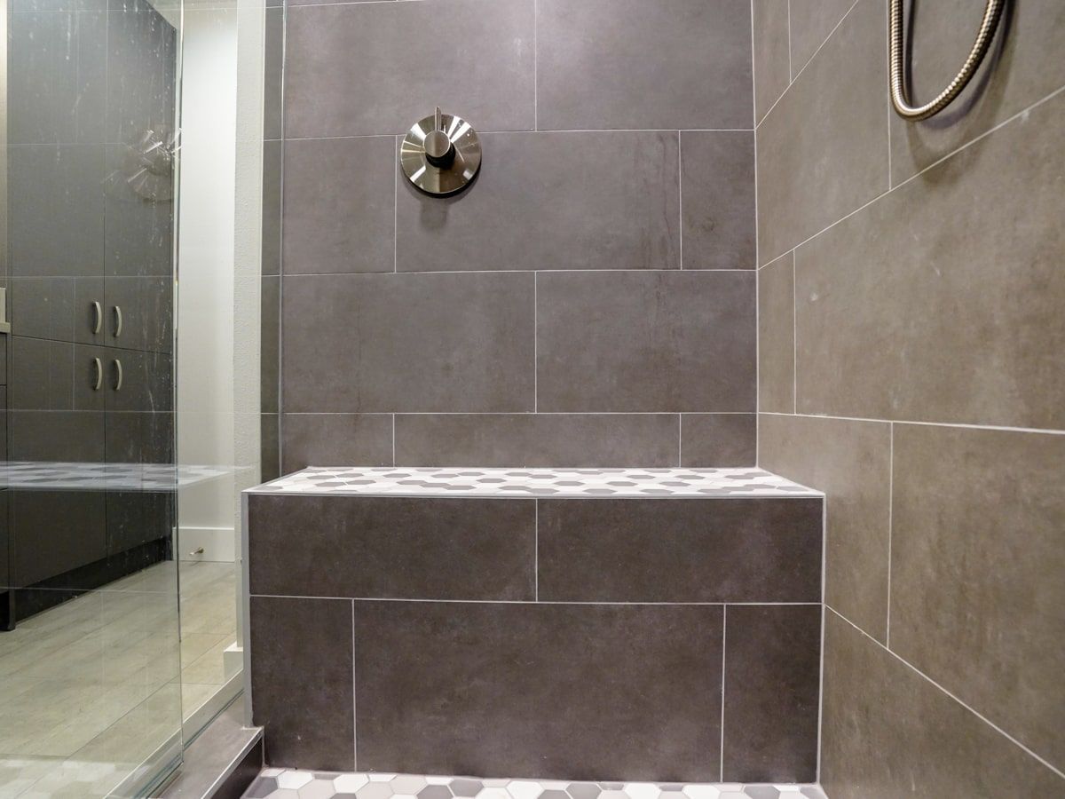 A bathroom with a walk in shower and a bench.