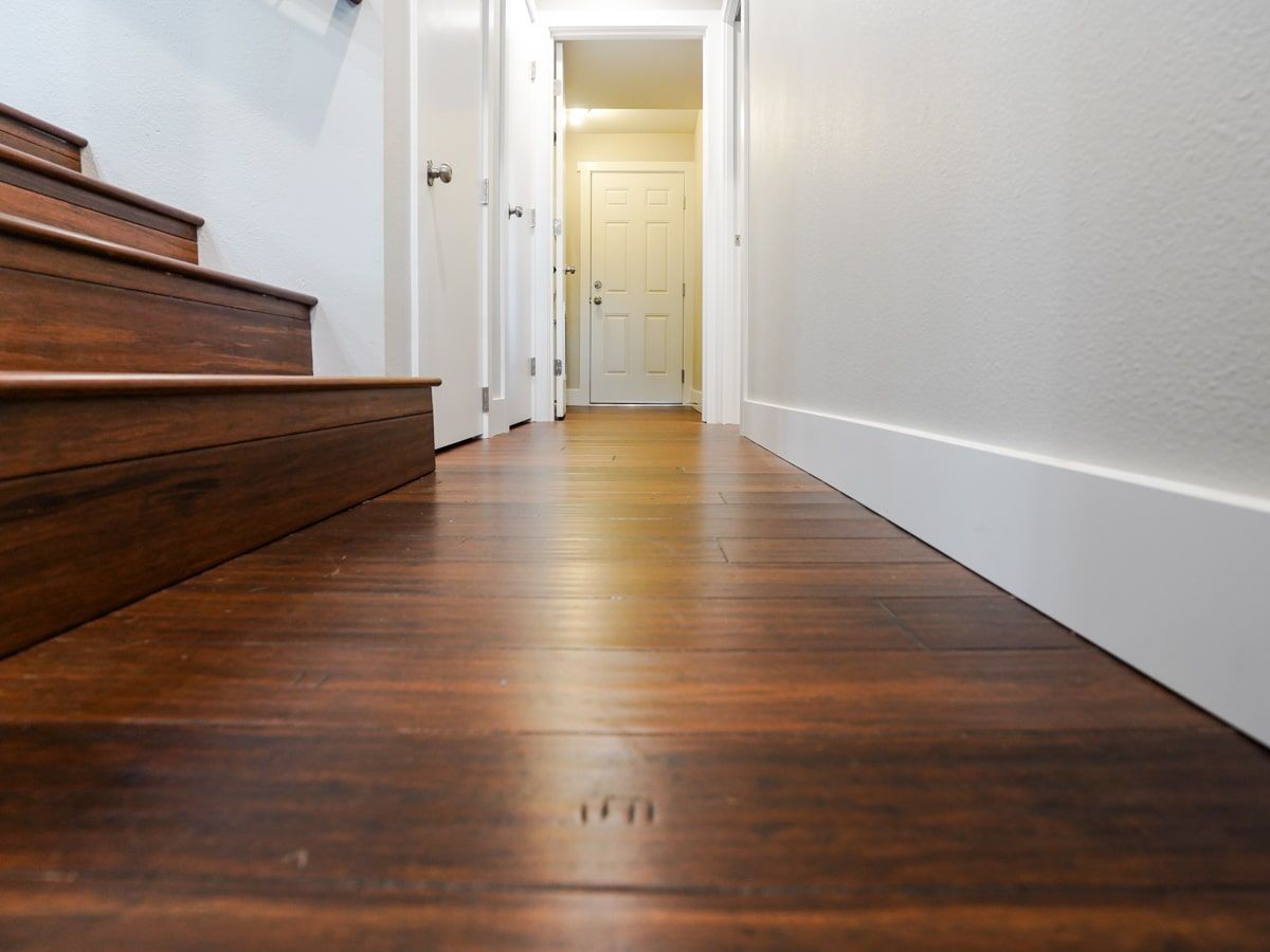 A hallway with wooden floors and stairs in a house.