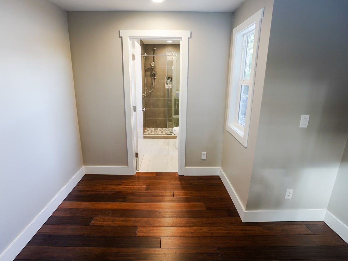 A hallway with hardwood floors leading to a bathroom