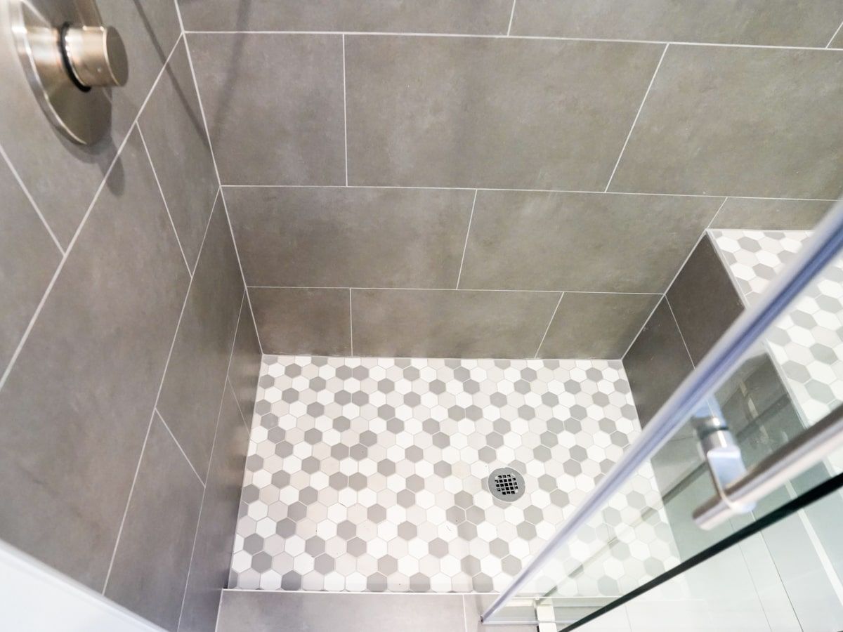 A shower stall with a glass door and a drain.