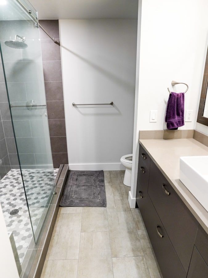 A bathroom with a walk in shower , sink and toilet.