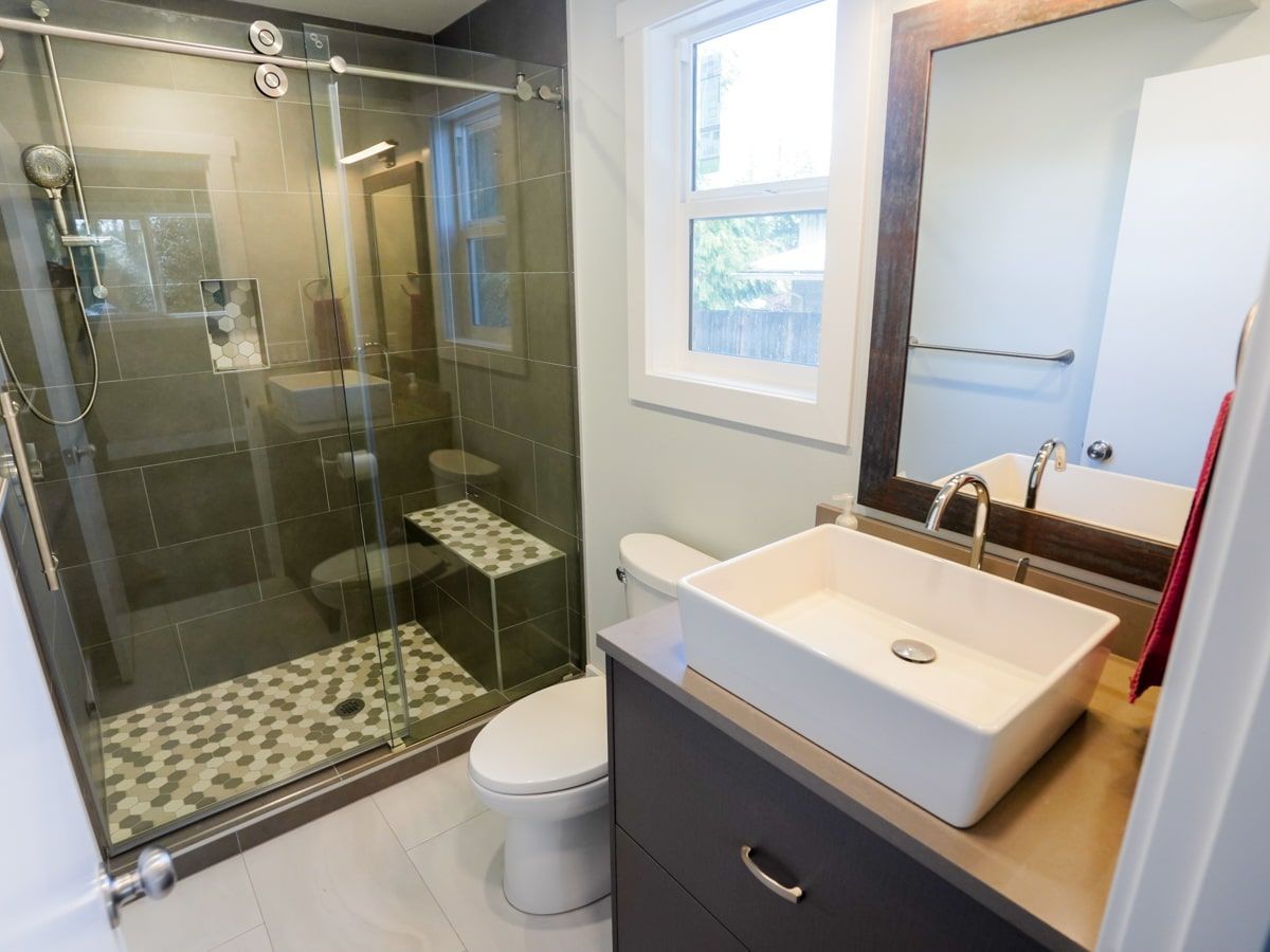 A bathroom with a sink , toilet , shower and mirror.