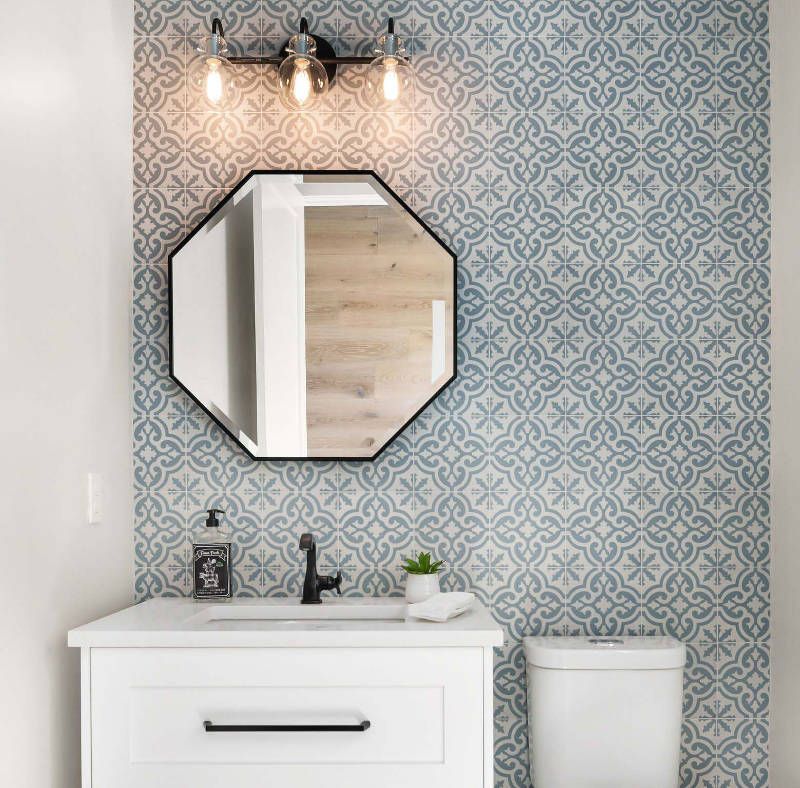A bathroom with a sink , toilet , mirror and light fixture.