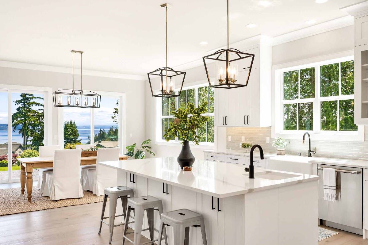 A kitchen with white cabinets and stools and a large island in the middle.