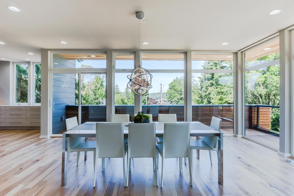 A dining room with a table and chairs and lots of windows