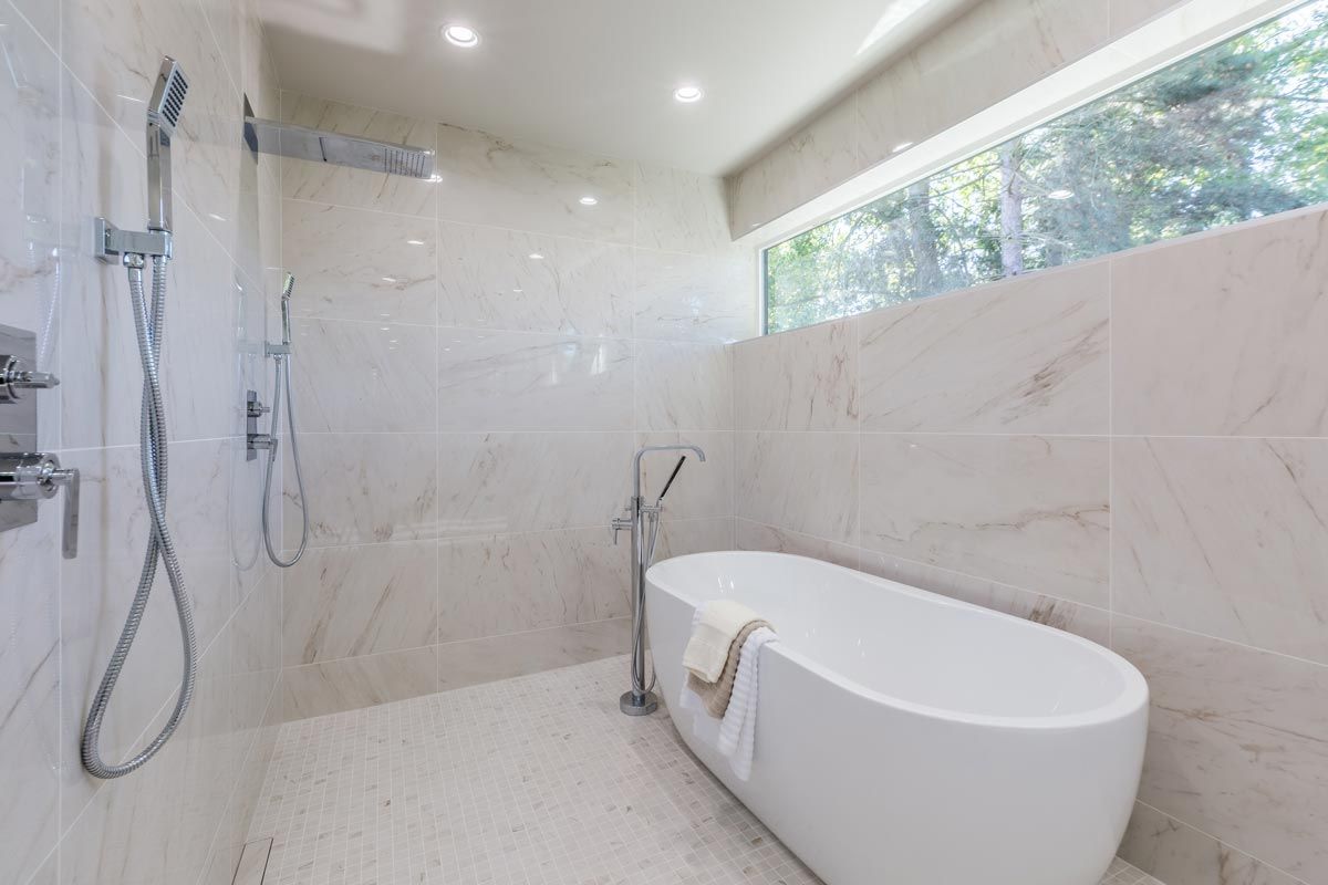 A bathroom with a tub , shower , and window.