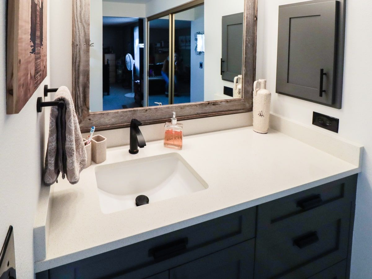 A bathroom with a sink , mirror and cabinets.