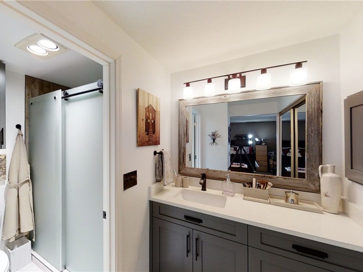 A bathroom with a sink , mirror and shower.