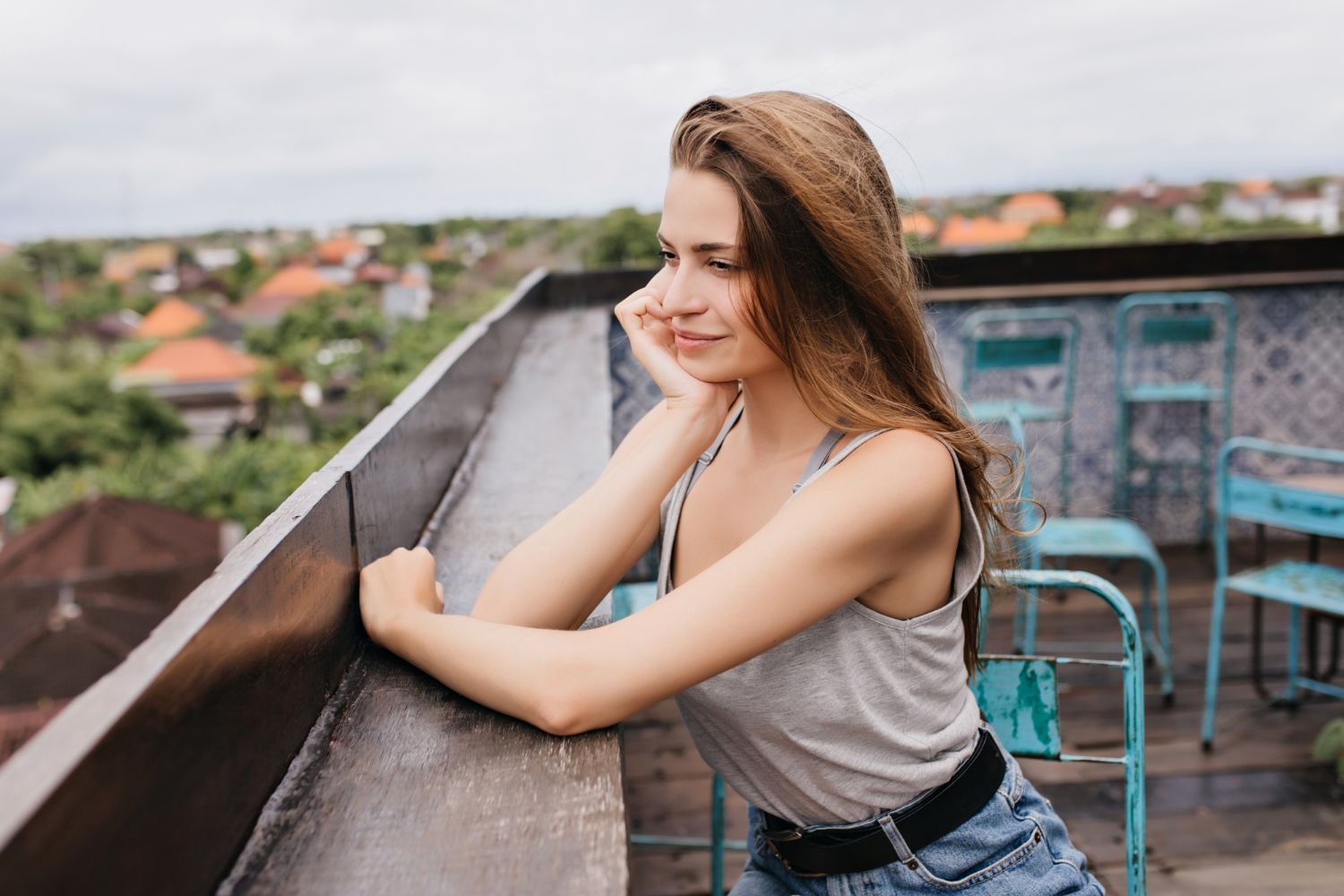 A woman is leaning on a railing on a balcony.