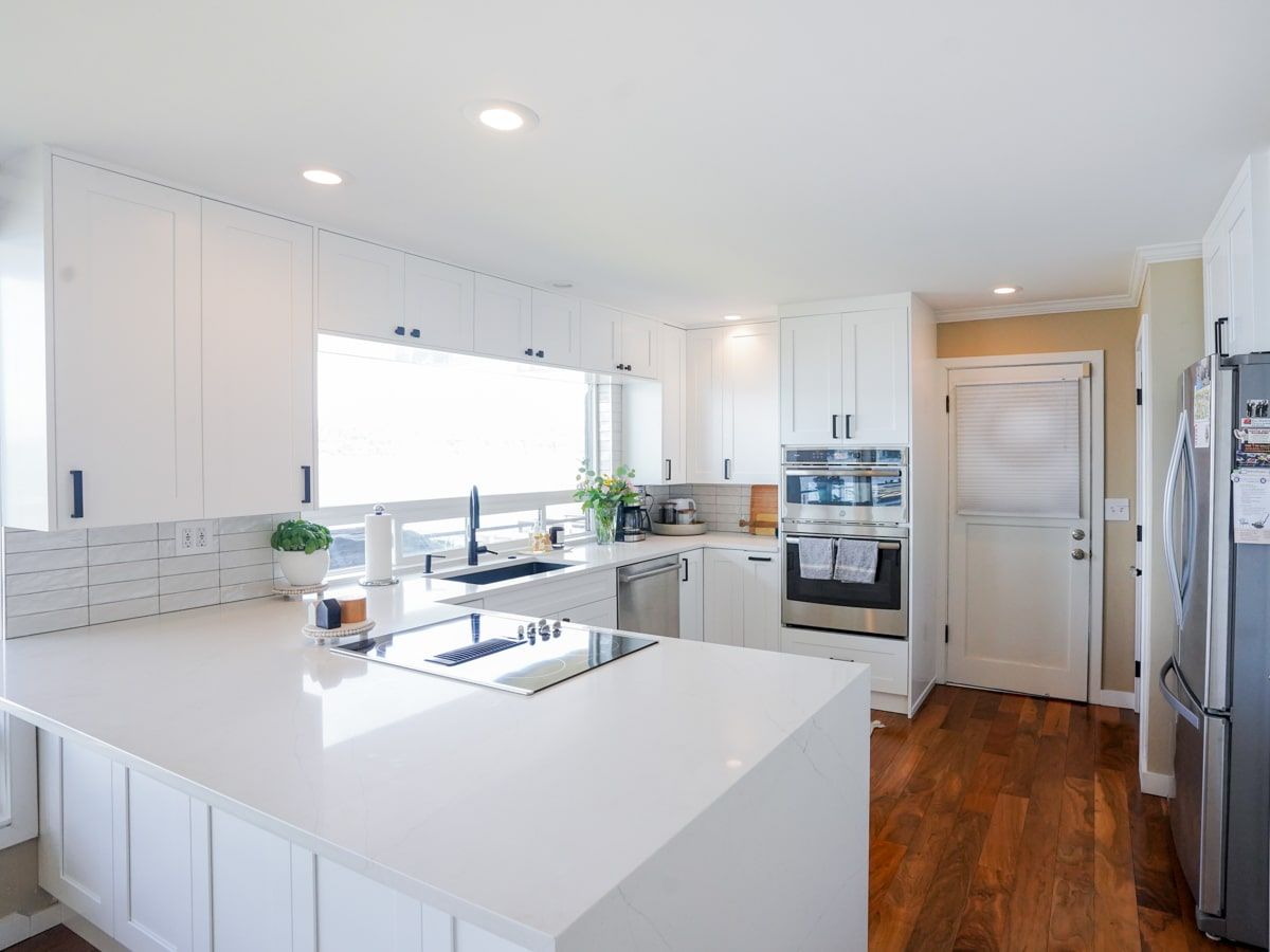A kitchen with white cabinets , stainless steel appliances , and hardwood floors.