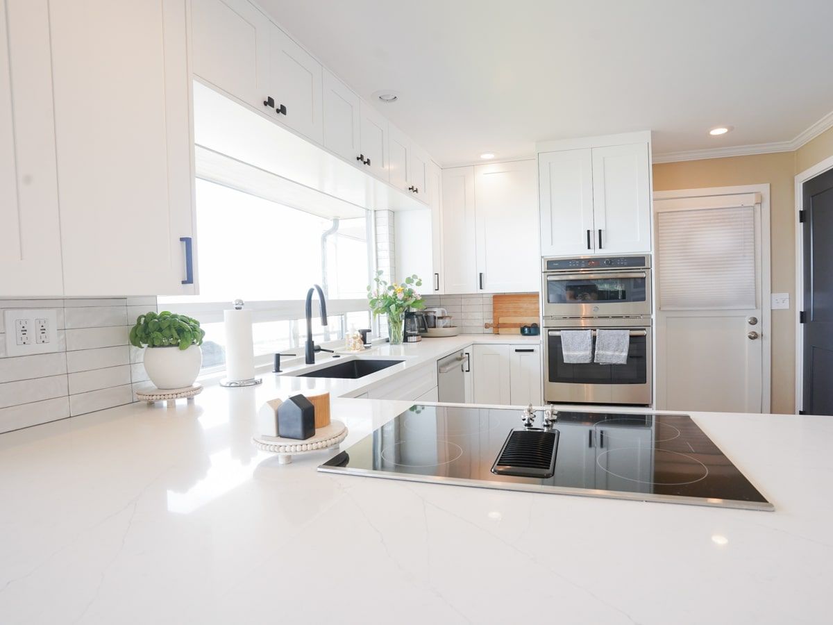 A kitchen with white cabinets , stainless steel appliances , a sink , and a stove top oven.