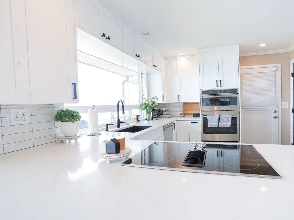A kitchen with white cabinets , stainless steel appliances , a sink , and a stove top oven.