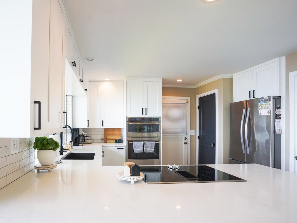 A kitchen with white cabinets , stainless steel appliances , and a stove top oven.