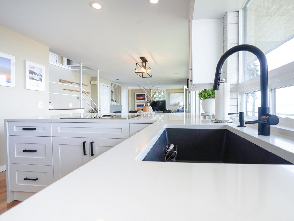 A kitchen with white cabinets and a black sink