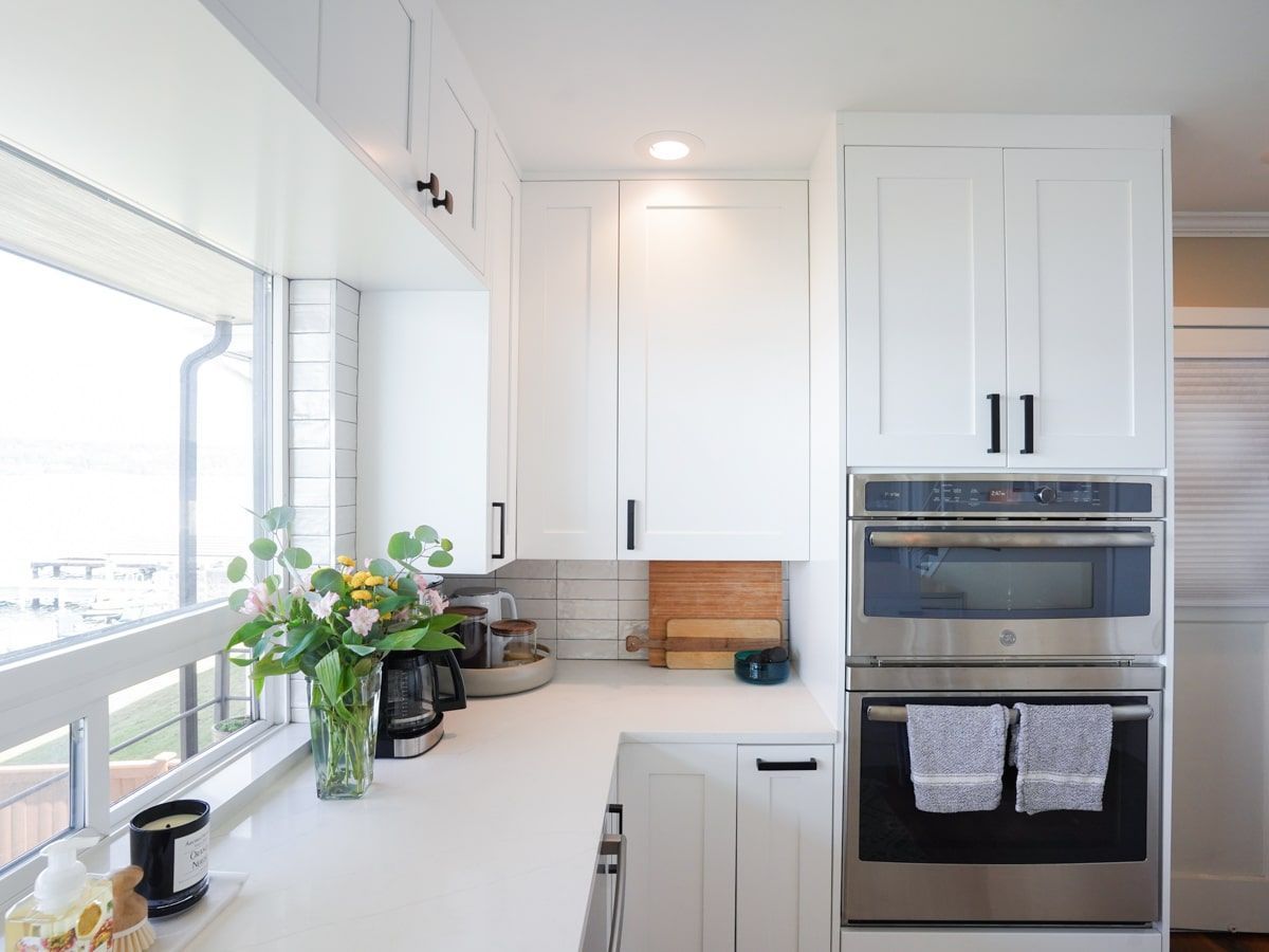 A kitchen with white cabinets , stainless steel appliances and a window.