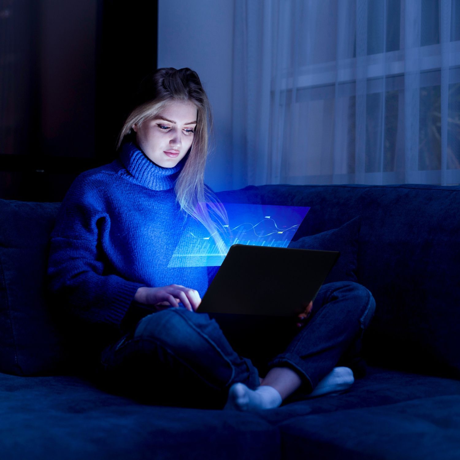 A woman is sitting on a couch using a laptop computer.