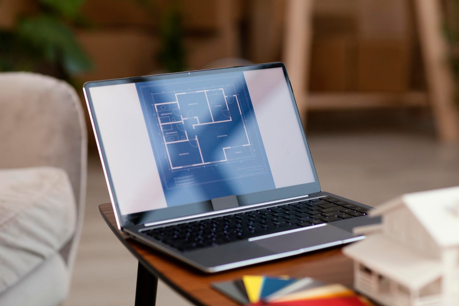 A laptop is sitting on a table with a blueprint on the screen.