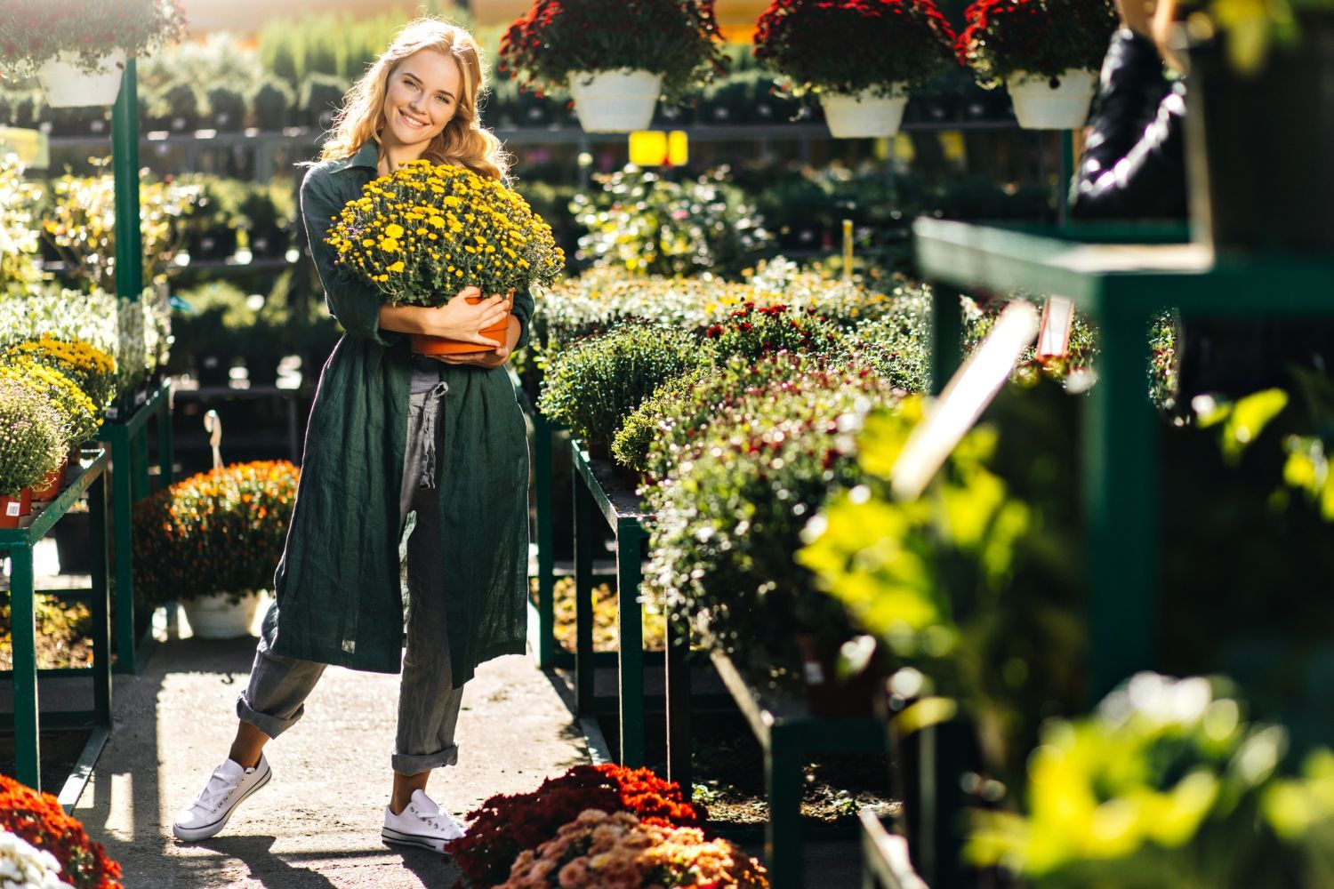 A woman is holding a potted plant in a garden center.