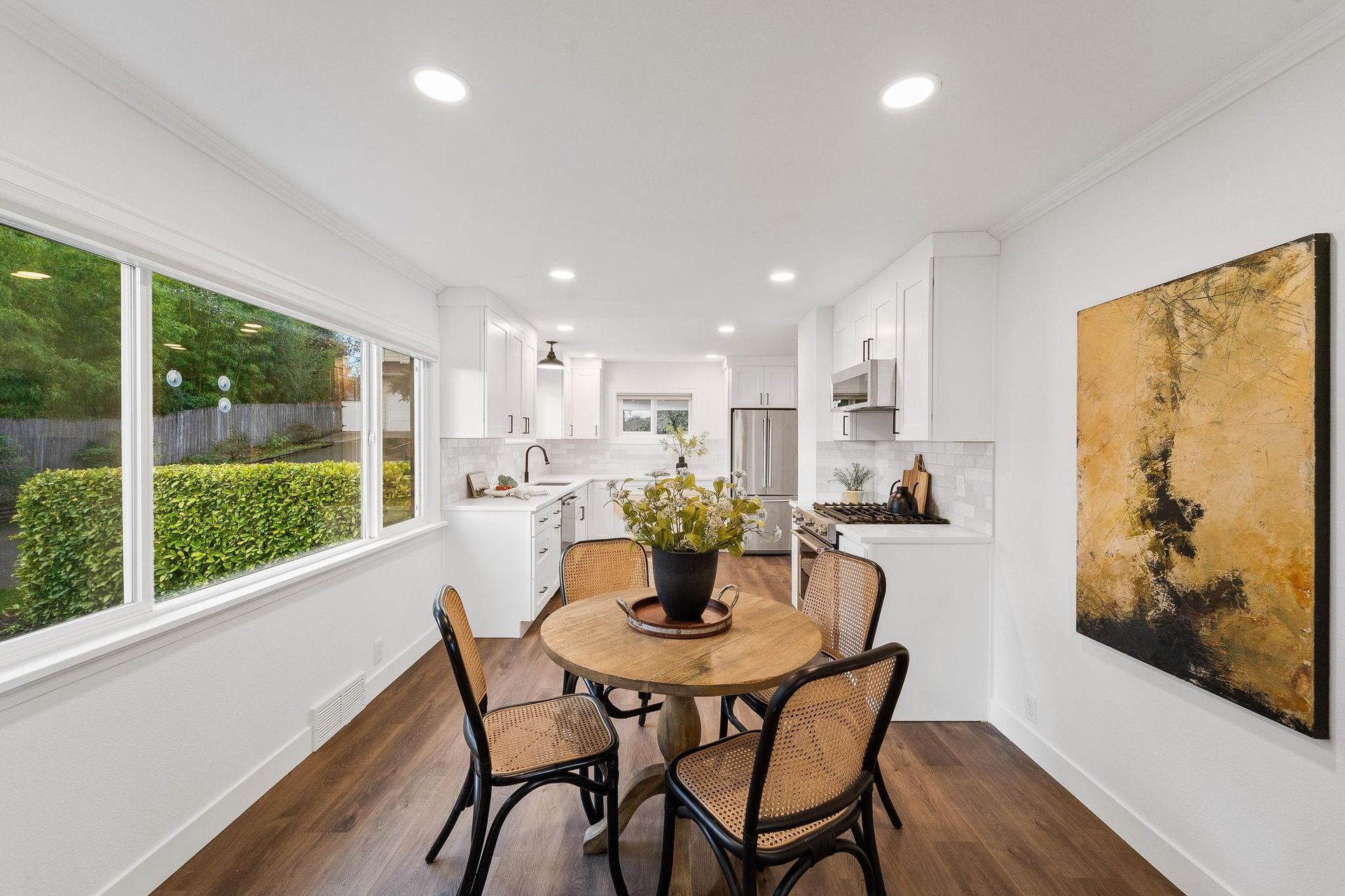 A dining room with a table and chairs and a painting on the wall.