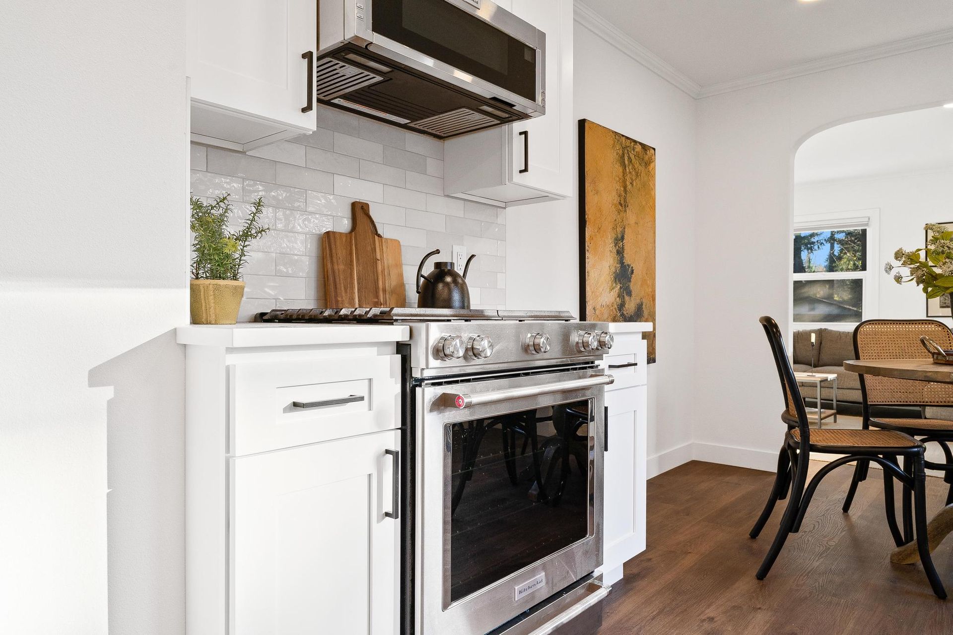 A kitchen with white cabinets , a stove and a microwave.