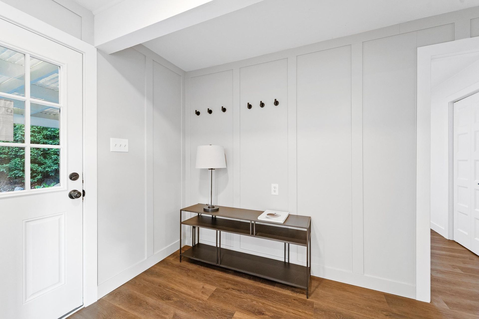 A hallway with a table and a lamp in front of a door.