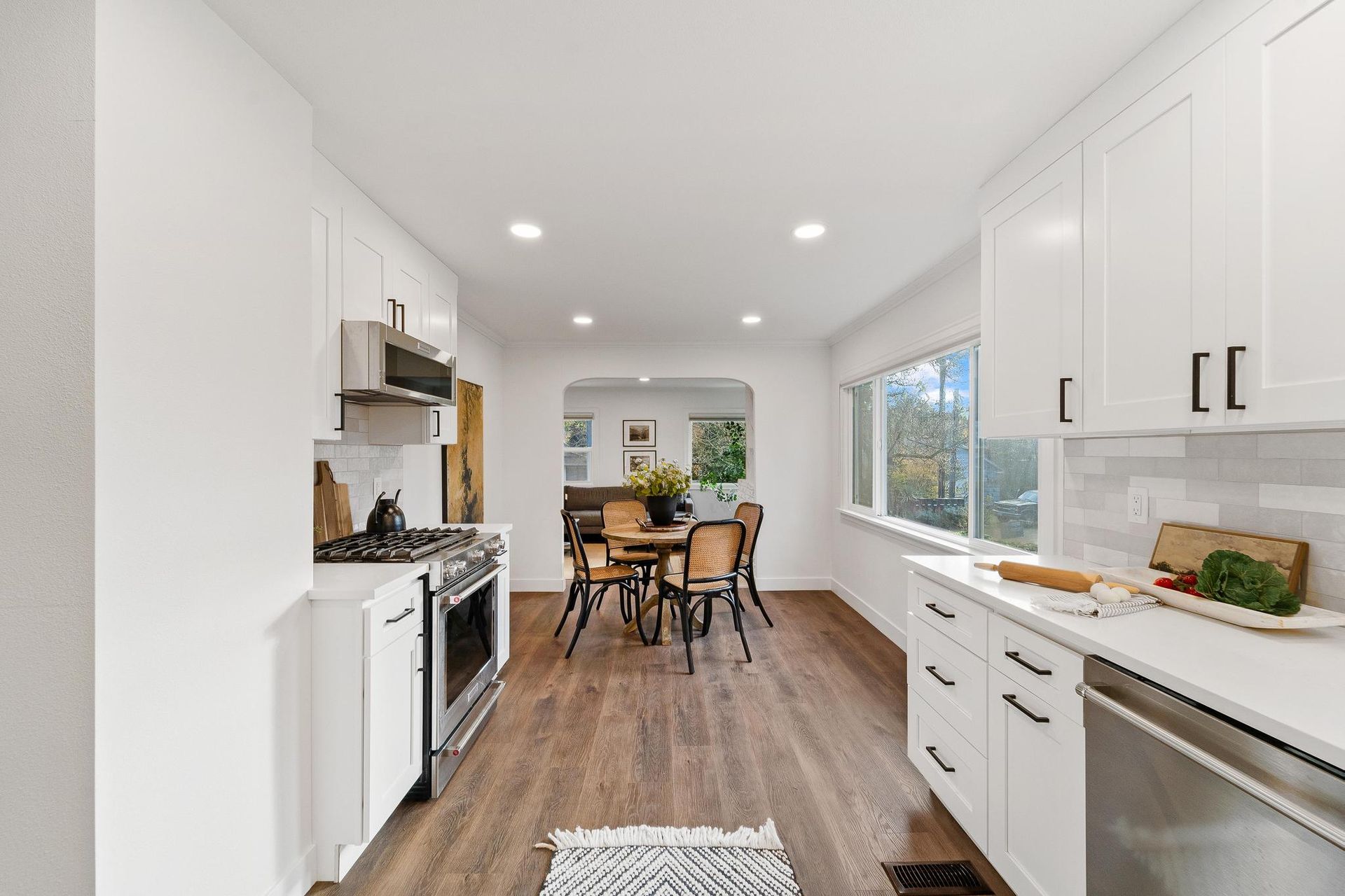 A kitchen with white cabinets and stainless steel appliances and a dining room in the background.