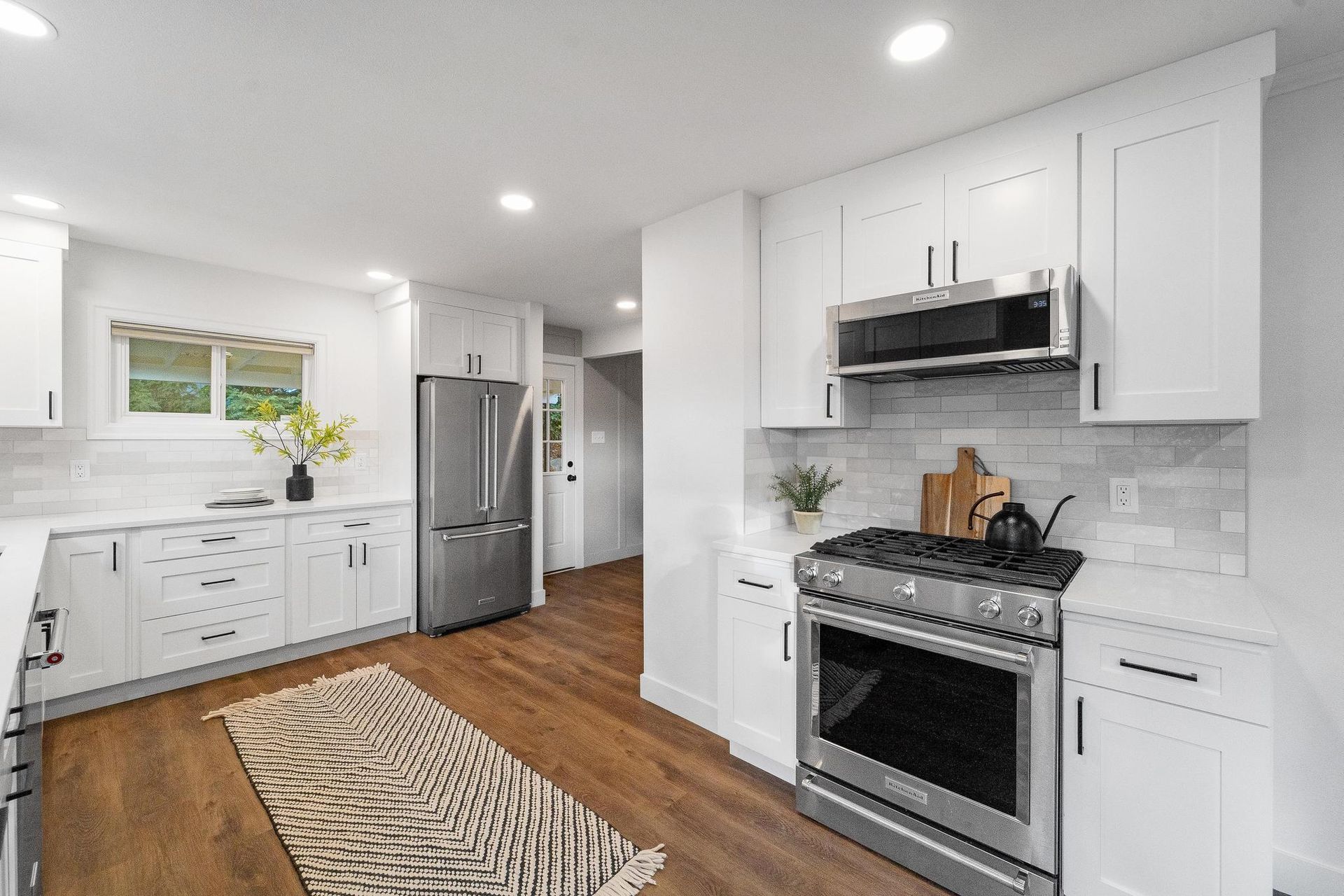 A kitchen with white cabinets , stainless steel appliances , and hardwood floors.
