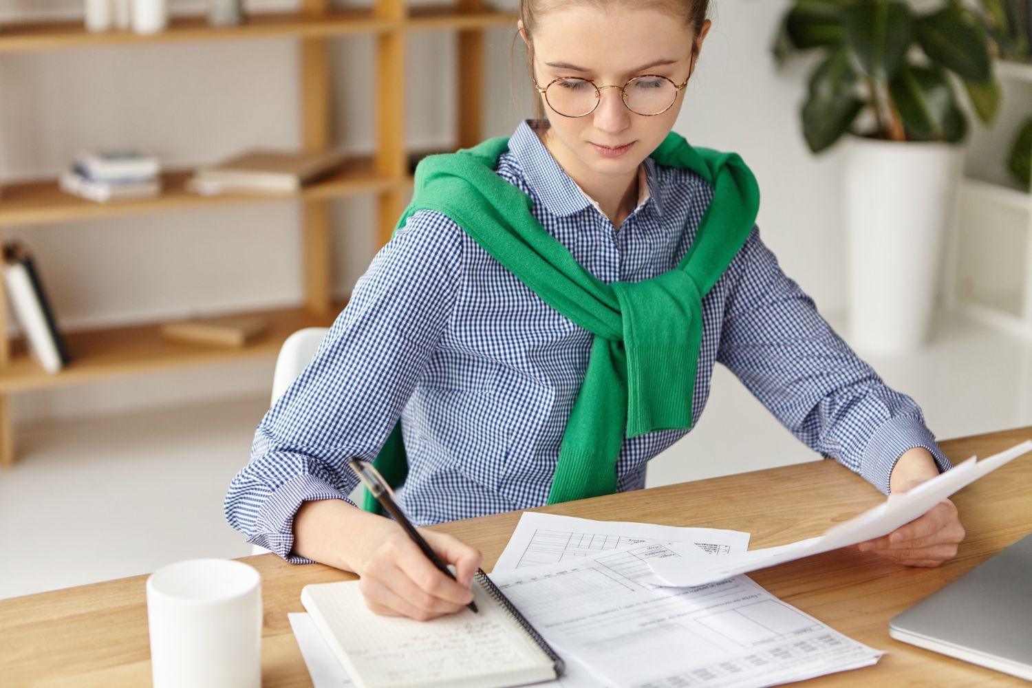 A woman is sitting at a desk writing in a notebook.