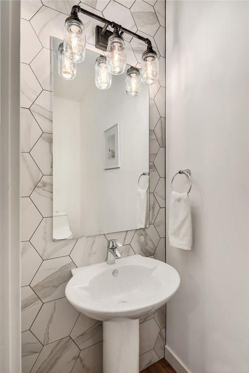 A bathroom with a sink , mirror and light fixture.
