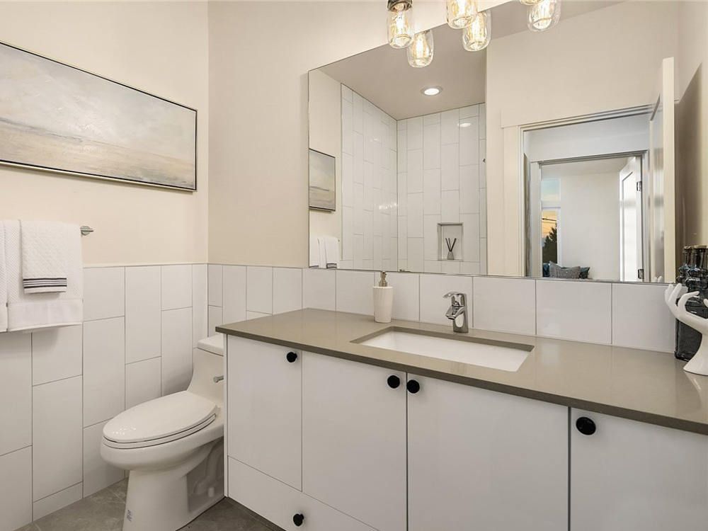 A bathroom with a toilet , sink and mirror.