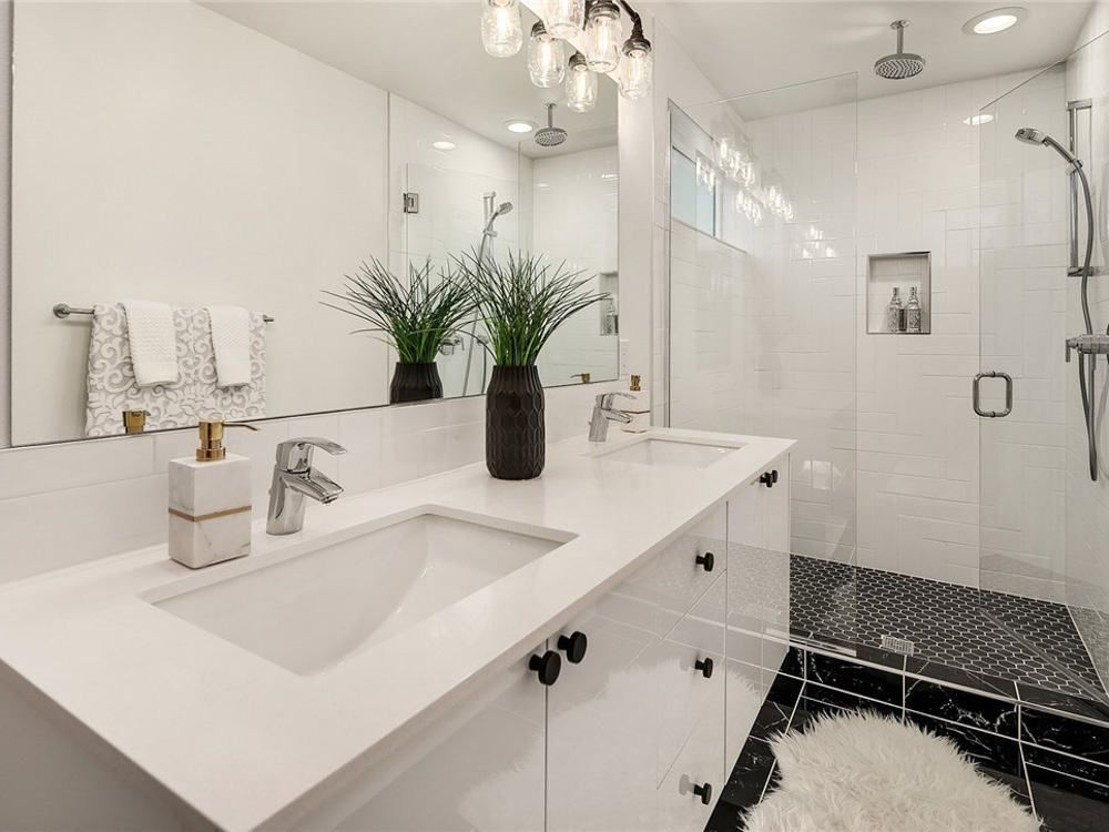 A bathroom with two sinks and a walk in shower.