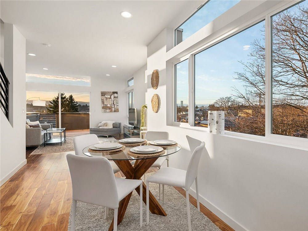 A dining room with a table and chairs and a large window.