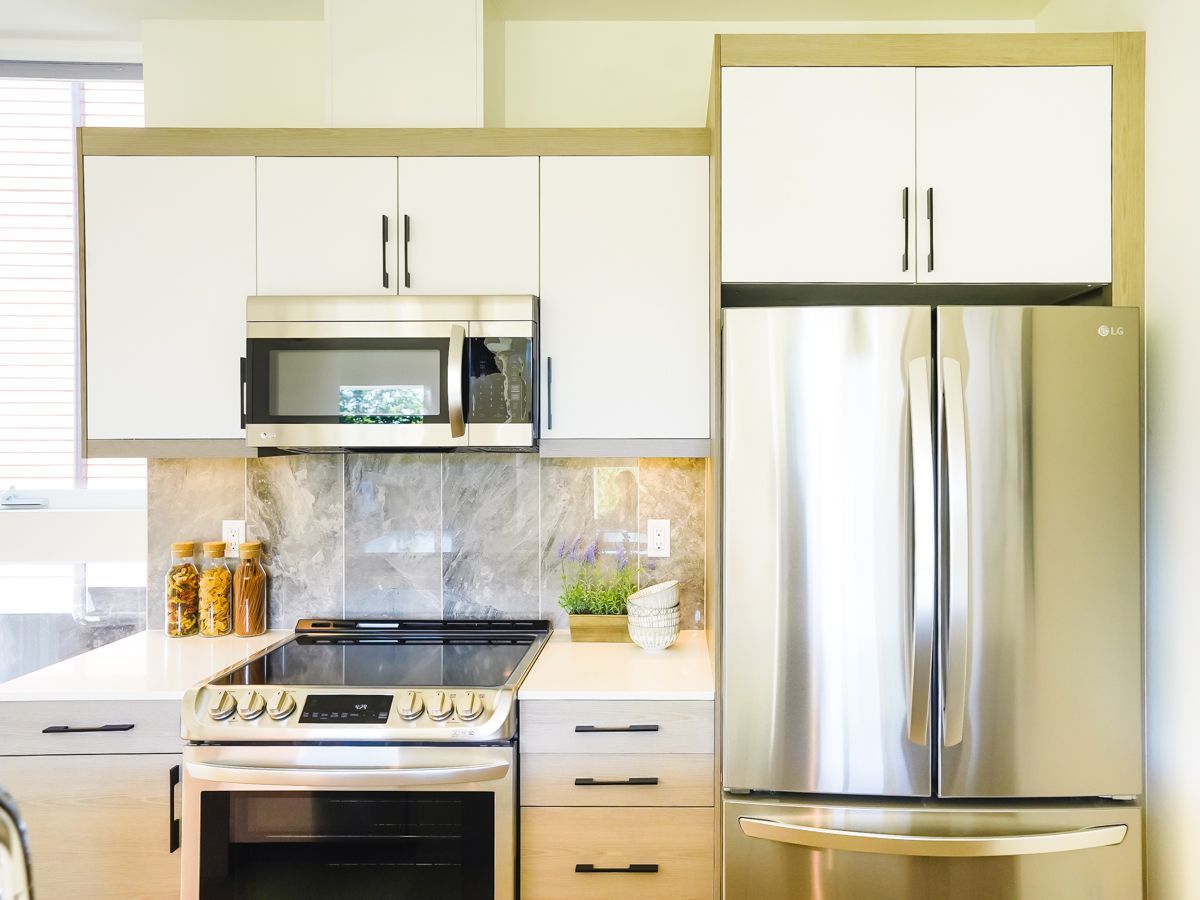 A kitchen with a stove , refrigerator , microwave and sink.