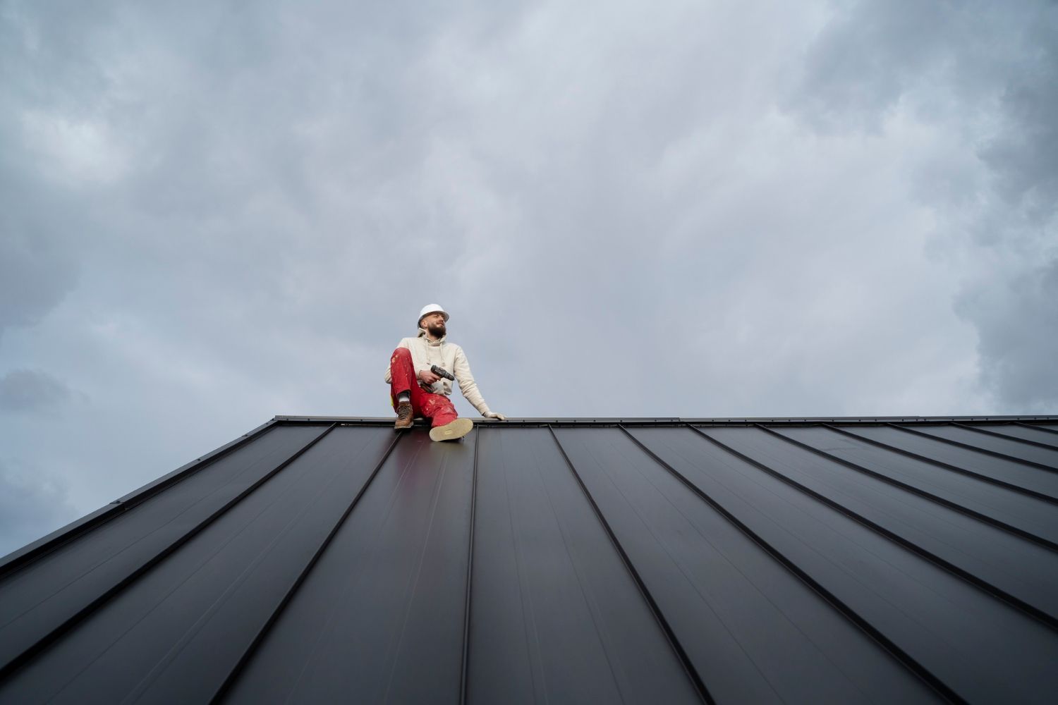A man is sitting on top of a black roof.
