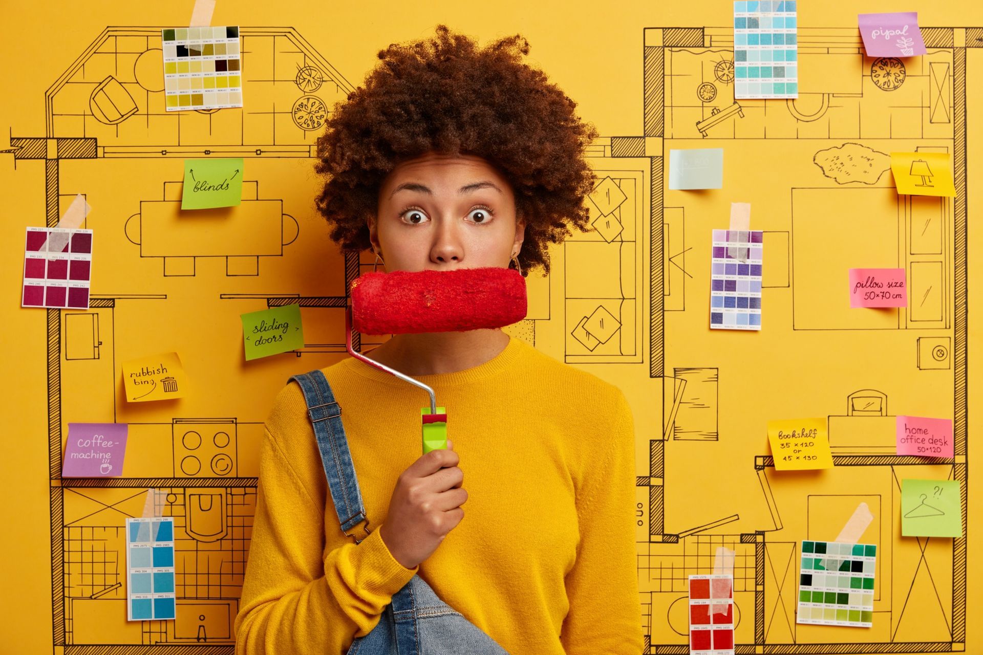A woman is holding a paint roller in front of her face.