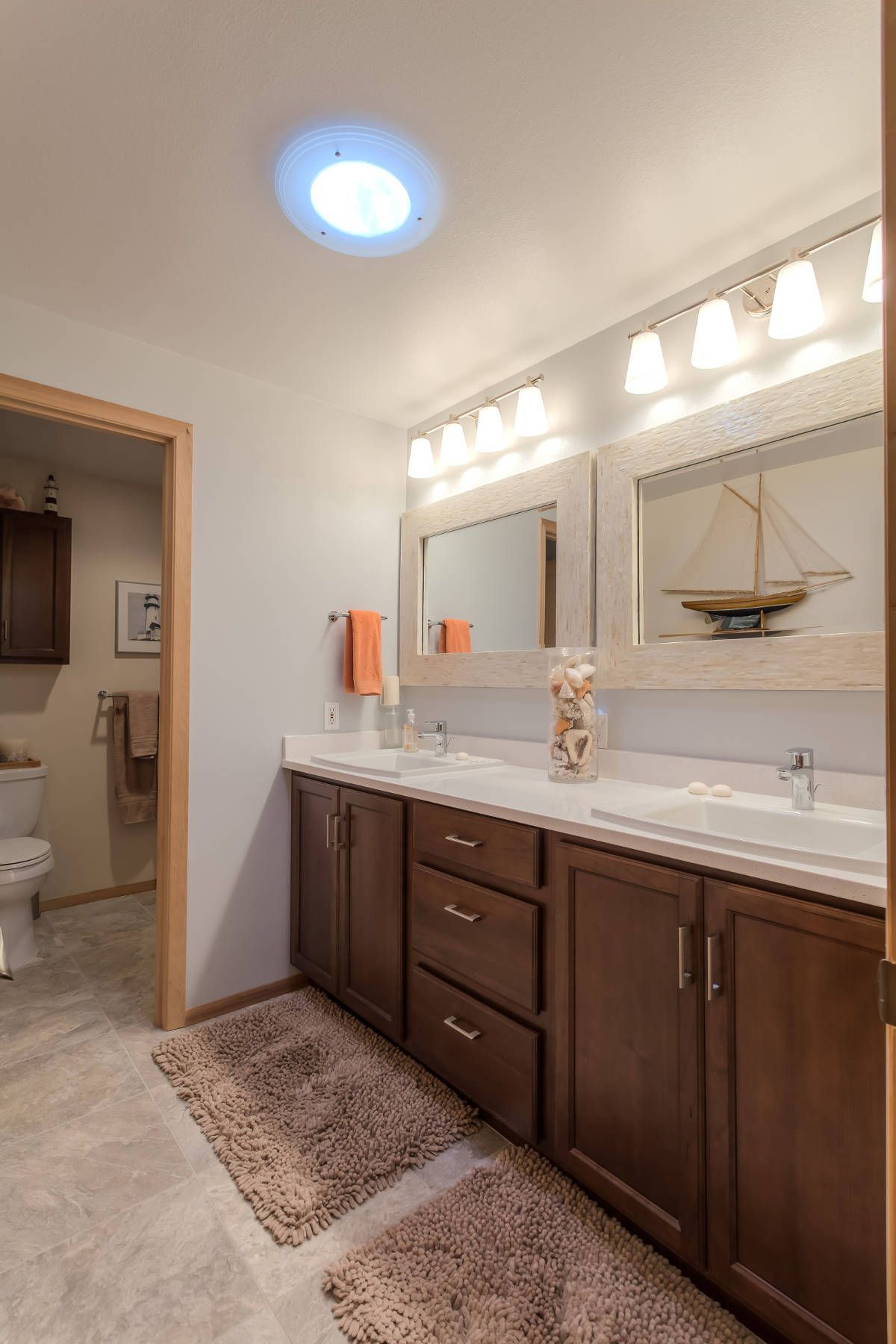 A bathroom with two sinks , two mirrors and a toilet.