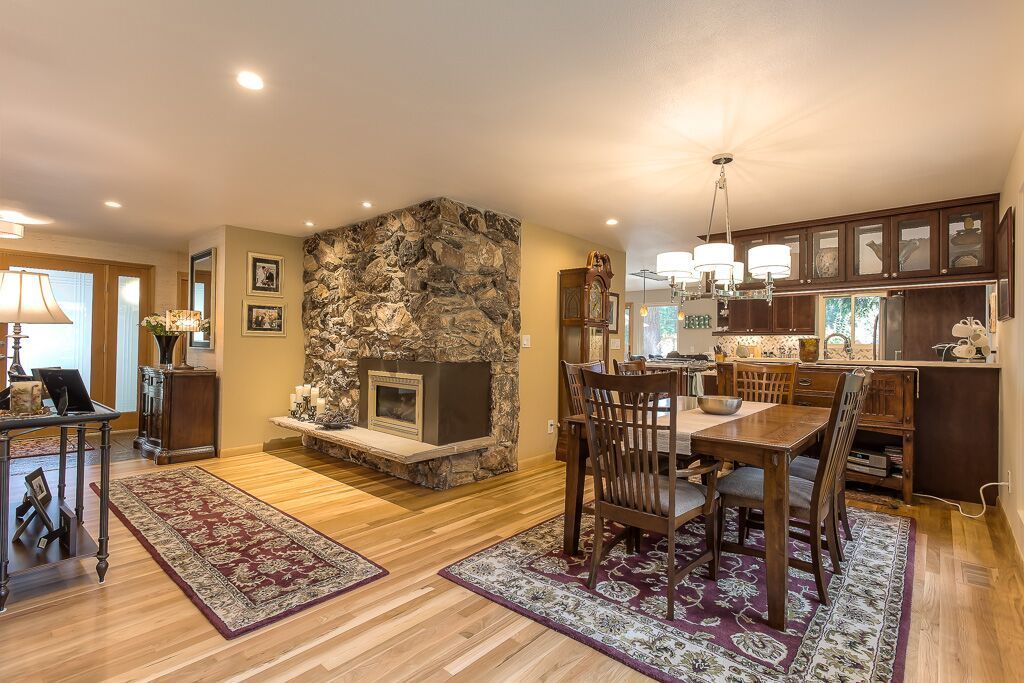 A living room with a dining room table and chairs and a fireplace.