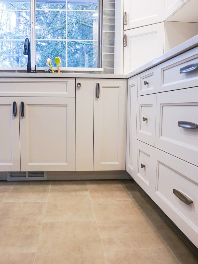 A kitchen with white cabinets and drawers and a window