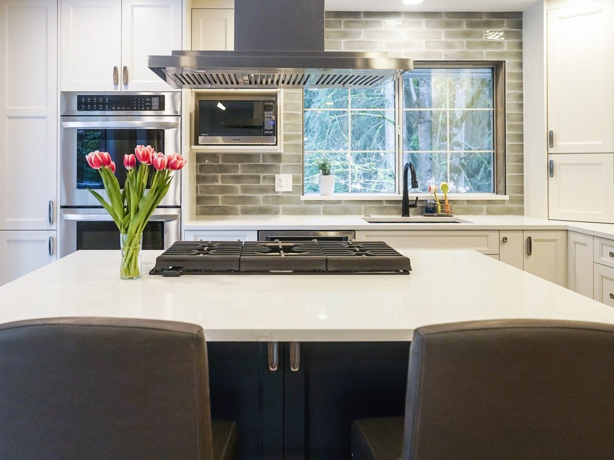 There is a vase of flowers on the counter in the kitchen.
