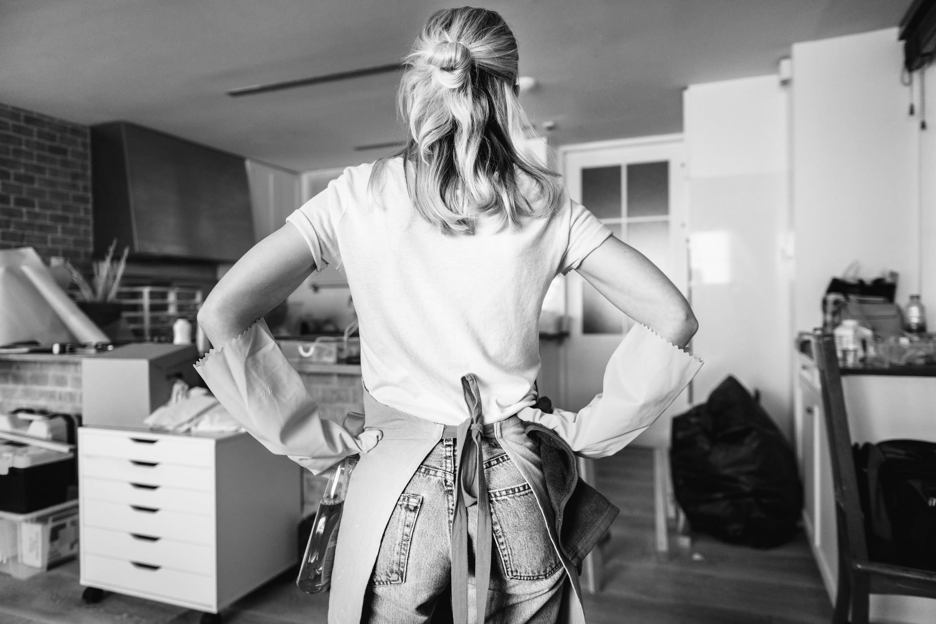 A woman is standing in a kitchen with her hands on her hips.