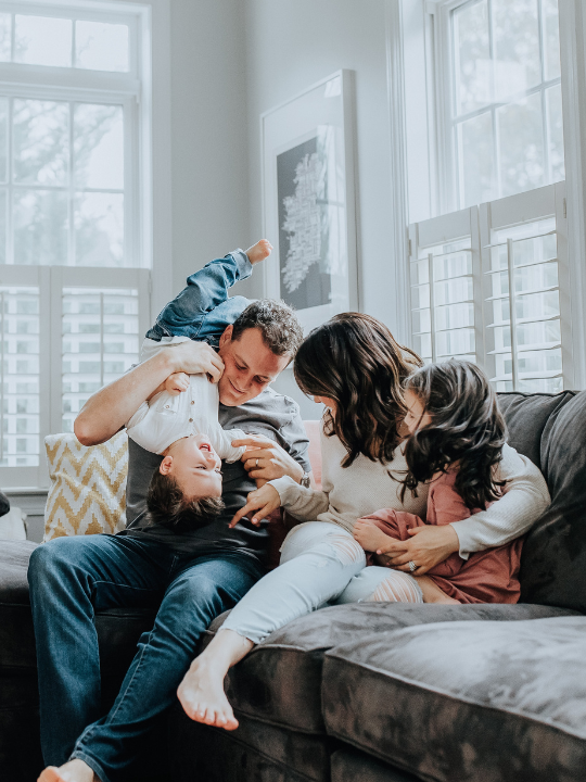 A family is sitting on a couch in a living room.